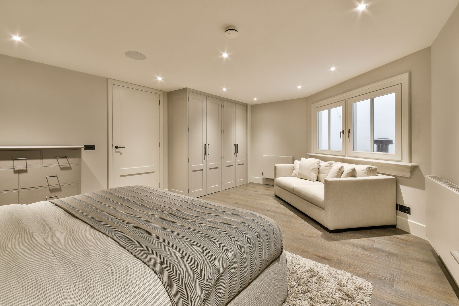 A renovated bedroom with slim steel-style window frames and a seating area